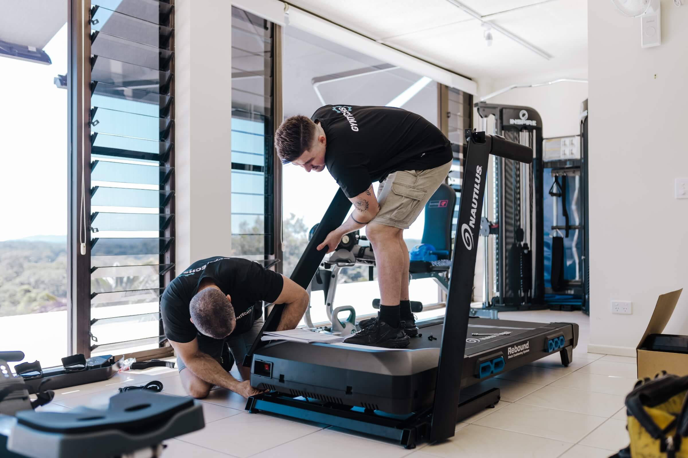 Two men installing a treadmill